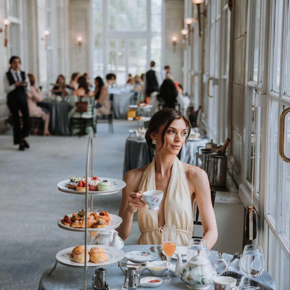 an elegantly dressed woman enjoying tea