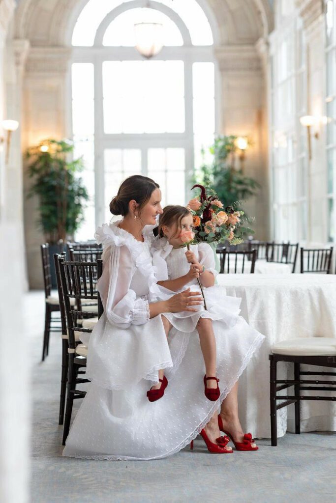 A woman in an elegant white dress sits with a young girl in her lap who is holding a rose in a luxury Nashville hotel dining room.