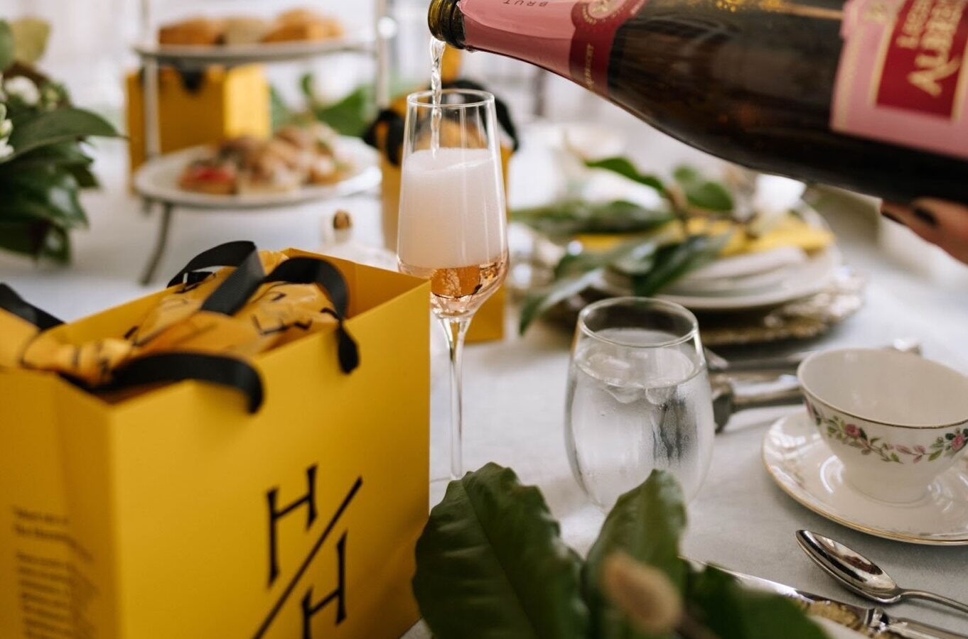 Champagne poured into flute beside yellow gift bag.