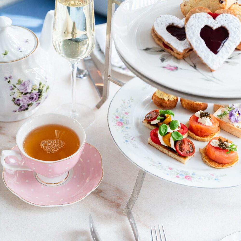 Afternoon tea with champagne, sandwiches, and heart-shaped pastries